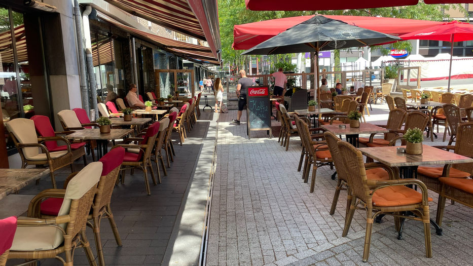 Gezellig terras van Welcome Geleen me fijne tafels en stoeltjes met kussentjes met een parasol voor fijne schaduw 
