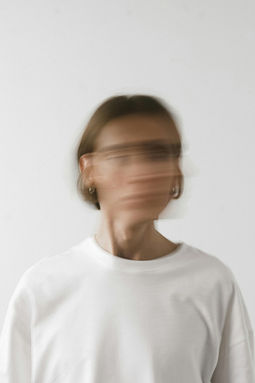 Blurred portrait of a person in a white shirt against a soft background