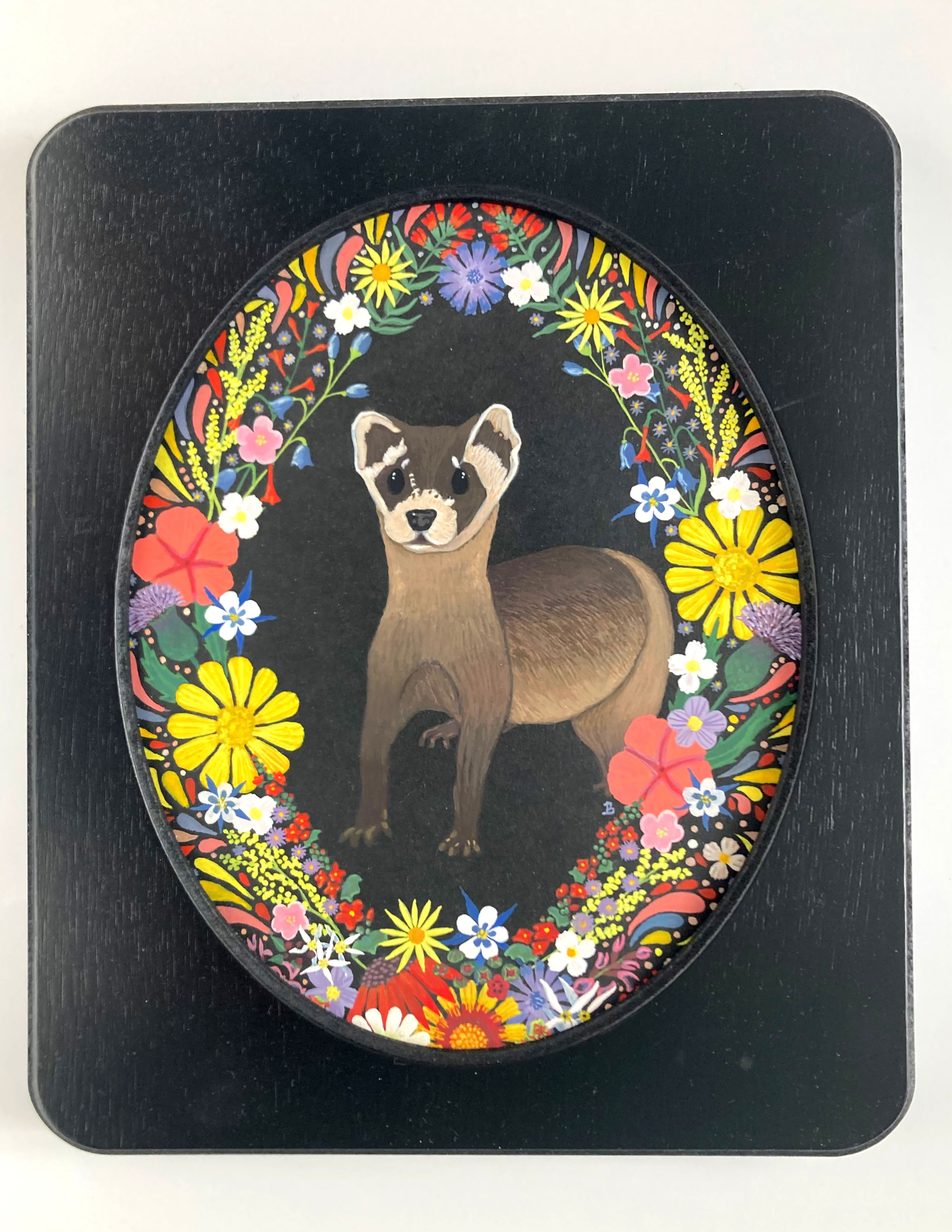 Oval wood framed painting of a black-footed ferret (centered) surrounded by Utah wild flowers