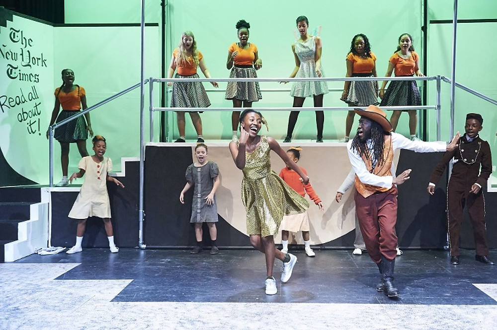 Black children perform on stage, dancing and singing for Theatre Peckham