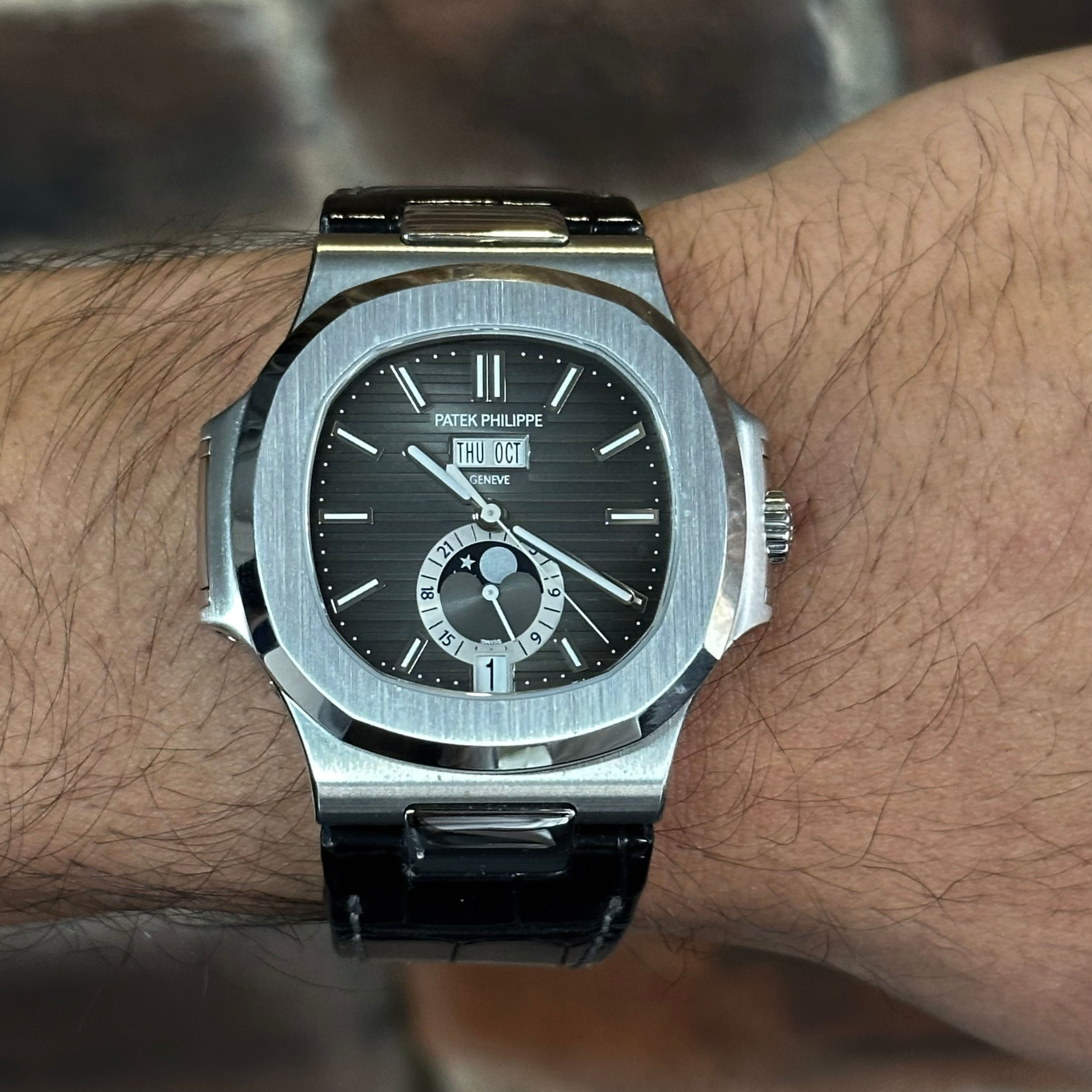 Patek Philippe Nautilus 5726A-001 Grey Black Dial, on a black leather strap, Being worn on a wrist