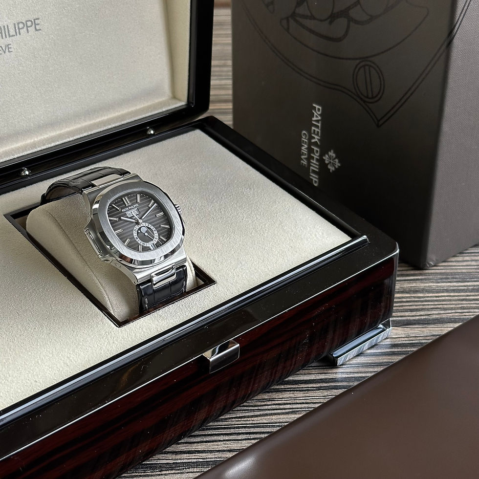 Thumbnail: Patek Philippe Nautilus 5726A-001 Grey Black Dial, on a black leather strap, being displayed in its box.