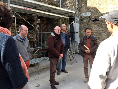 Plusieurs personnes réunies devant un échafaudage et des murs en pierre sur un chantier ancien.