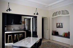 Intérieur de l'Appartement Bleu Blanc rénové, avec moulures au plafond, murs clairs et éléments de serrurerie noire.