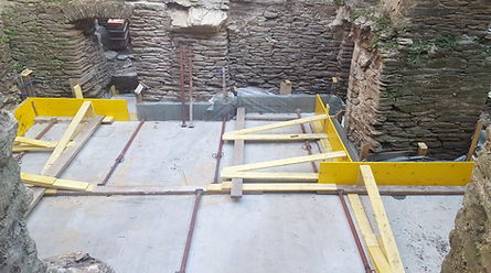 Vue en plongée d'une dalle béton neuve entourée de murs en schiste et d'éléments de coffrage.
