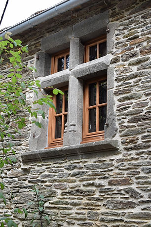 Fenêtre à meneaux à quatre baies, encadrement en granit et menuiseries bois dans une façade de schiste.