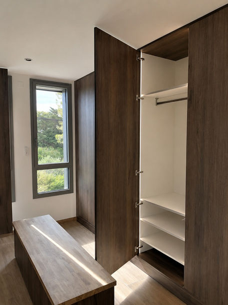Dressing sur mesure avec placards intégrés en bois, éclairage intérieur et banc central.