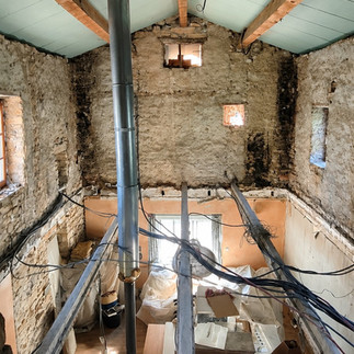 ntérieur d'une ancienne bâtisse en pierre avant travaux avec plancher intermédiaire divisant le volume sous toiture