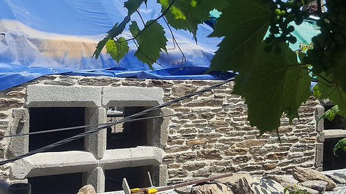 Façade en schiste en cours de restauration avec encadrement de fenêtre à meneaux en granit nouvellement posé.