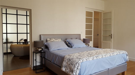 Chambre ouverte sur une salle de bains avec verrière en acier dans un appartement à Nîmes