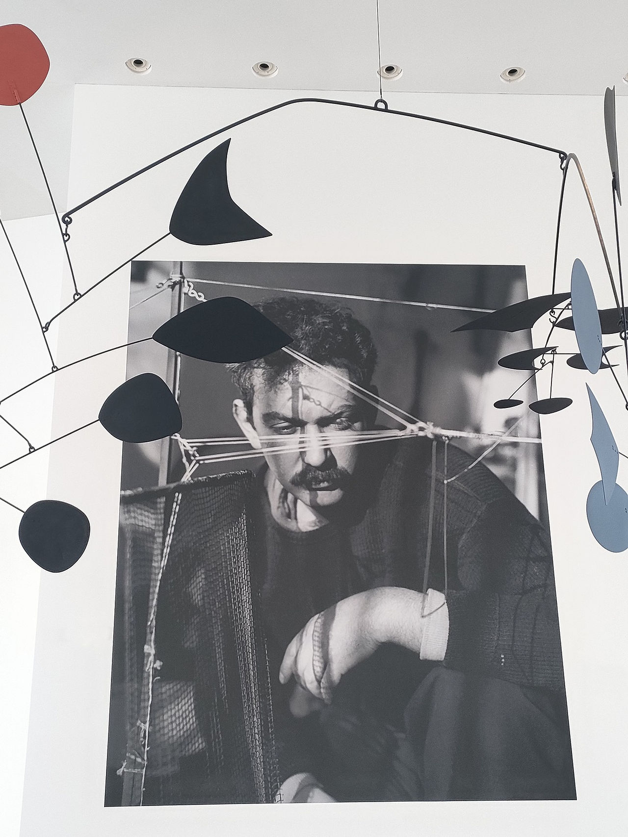 Portrait en noir et blanc d’Alexander Calder entouré de mobiles à la Fondation Louis Vuitton
