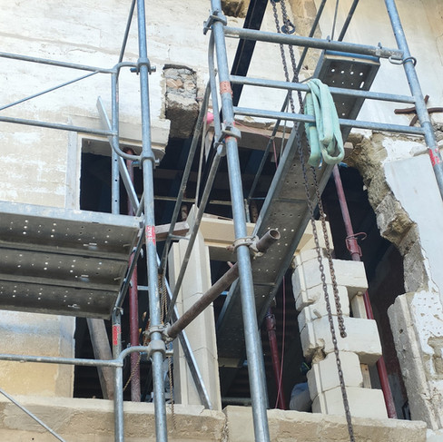 Mise en œuvre des meneaux en pierre sur chantier de rénovation patrimoniale.