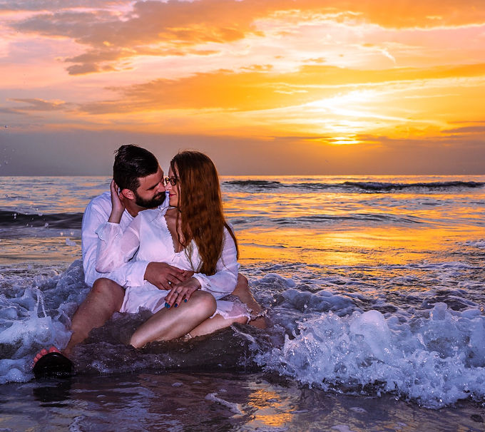 a couple posing in the water in clearwater beach as a wave comes in towards them