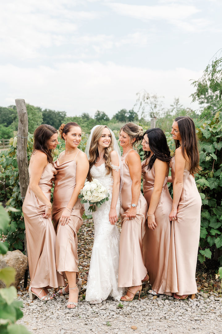 Bride laughing with bridesmaids in blush dresses at White Birch Barn in Medina, Ohio