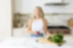 Registered Dietitian Shavonne Wood standing in a kitchen with fresh produce on the counter and holding a drink.
