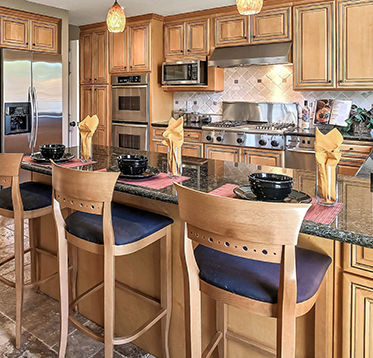 Modern kitchen with wooden cabinets, stainless steel appliances, and island with stools.