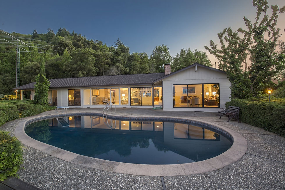 Modern single-story house with a kidney-shaped swimming pool at dusk.