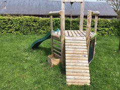 Front view of a wooden swing and slide
