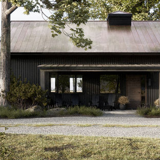 Dark modern cabin exterior with a porch and surrounding greenery. By Black Cabin.