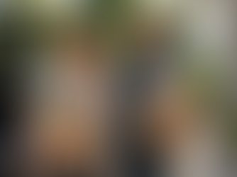 A smiling middle-aged mixed-race couple carries grocery bags filled with fresh, protein-rich foods as they walk from their car toward their home on a sunny afternoon, highlighting the strength and vitality needed for everyday life after 40.