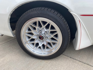 A white 1980s Trans Am wheel with the Firebird emblem in the middle.