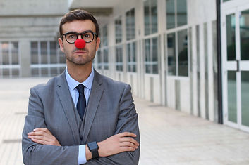 Serious looking businessman or teacher with a red nose. Laugh Therapy workshops.