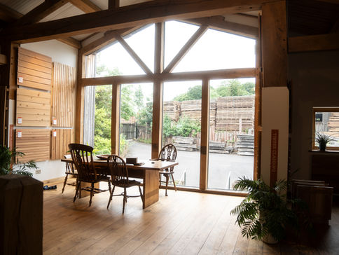 View from inside Vastern Timber showroom. Light flooding in looking through four tall timber framed windows on to the timber yard