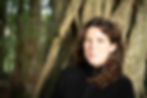 A colour photo of Catherine Byrne against a tree trunk