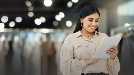Fashion retail professional using a tablet to check stock on the shop floor while managing inventory across sales channels