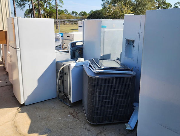 White appliances and air conditioners ready for recycling at a facility.
