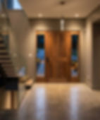 Contemporary foyer with wooden door and glass staircase