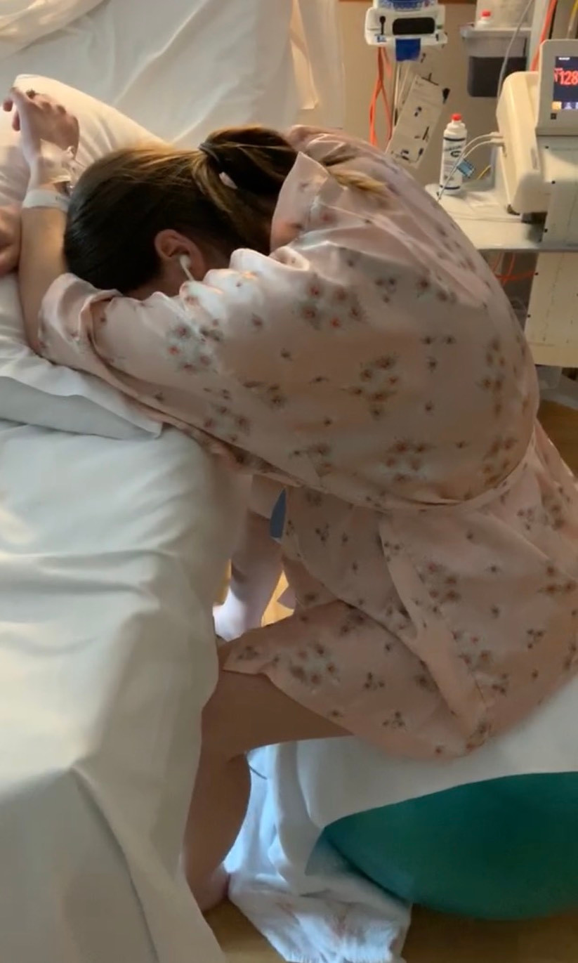 Georgia leaning over the bed breathing through surges and contractions during labour