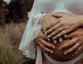 Picture of a pregnant belly with mum and dad holding their baby