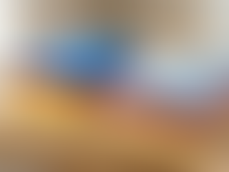 Folded shirts in bright colors stacked beside similar shirts with faded, washed-out colors on a wooden table.