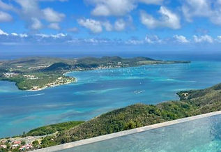 Luxury bareboat sailing yachts and catamarans anchored near palm-fringed beaches in a beautiful bay in Martinique.