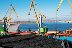 Loading of coal by buckets (grabs) of portal cranes into the holds of a dry cargo ship in
