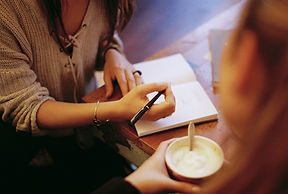 woman's hands writing in a notebook, while talking to client