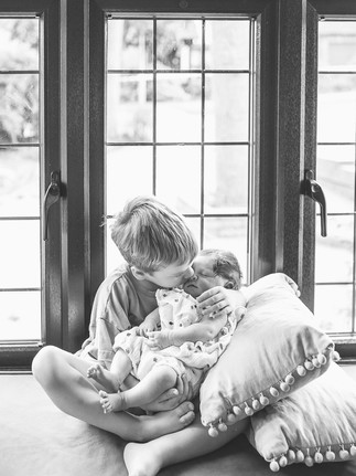 A big brother cuddling his new baby sister during a newborn and sibling photography session.