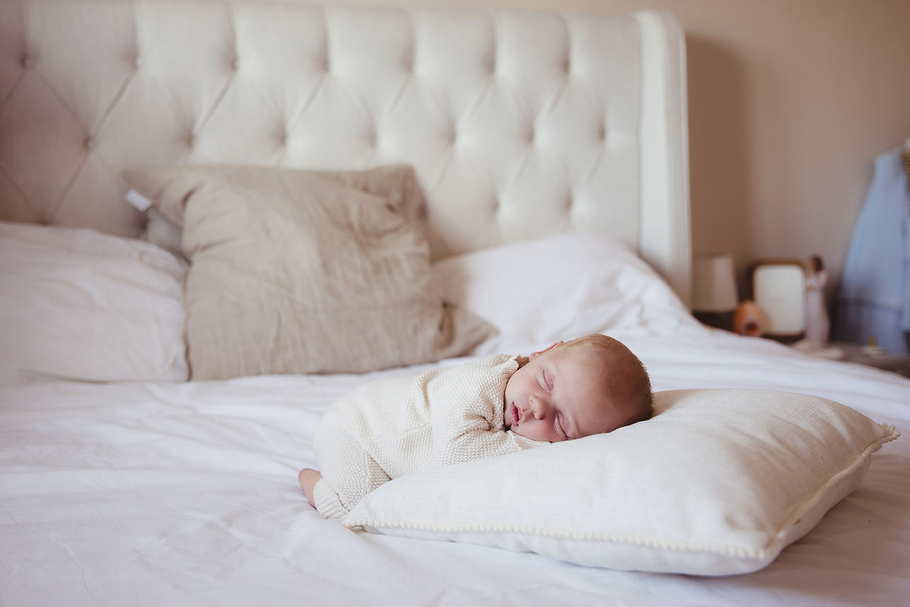 A newborn baby sleeping on a bed at a newborn photoshoot at home in Essex.