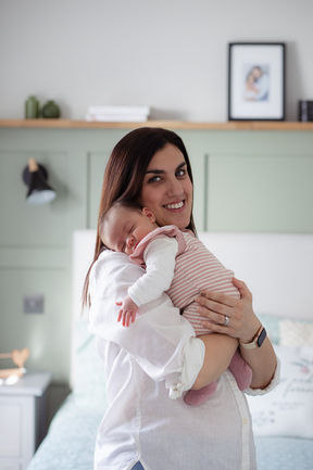 A woman holding her baby over her shoulder during  a newborn and family photography session in Essex. 