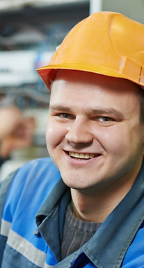 Man in hard hat and overalls smiles.