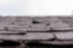 Damaged roof with missing shingle, cloudy sky in background. Roof Repair.