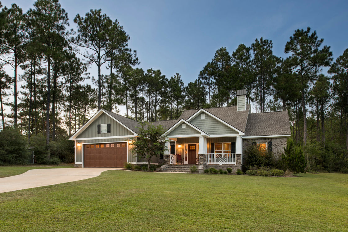 Exterior view of a beautiful, spacious house with green lawn and trees.