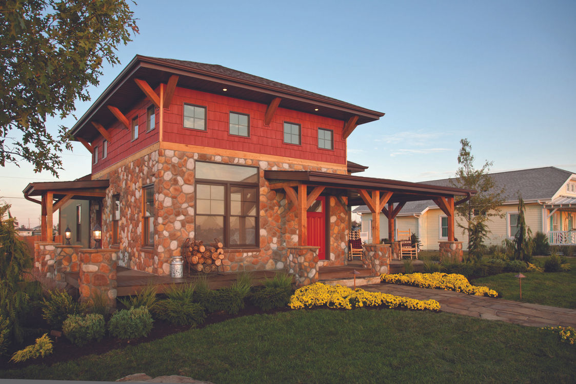Red house with stone facade, windows, and front door, in the evening light.