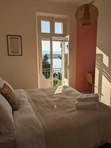 Peaceful bedroom with rose colored walls, overlooking a sunrise over the Mediterranean Sea in the South of France.