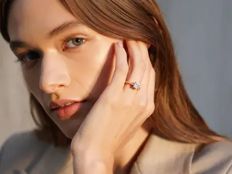 Mujer con piel clara cabello castaño claro mostrando su anillo de compromiso oro 18k en la mano, estilo elegante y natural.