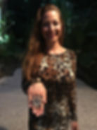 Sanaz smiling wearing a leopard print dress and displaying a large ornate ring.