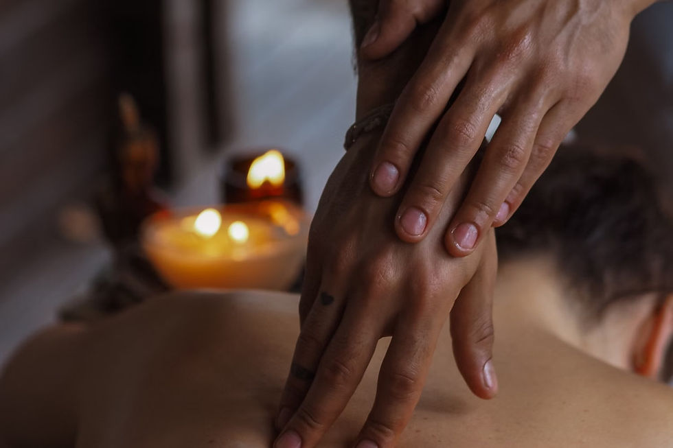 Massage therapist's hands on a person's back with candles.
