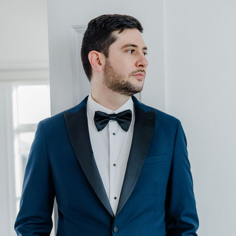 Marcio wearing a navy tuxedo and black bow tie