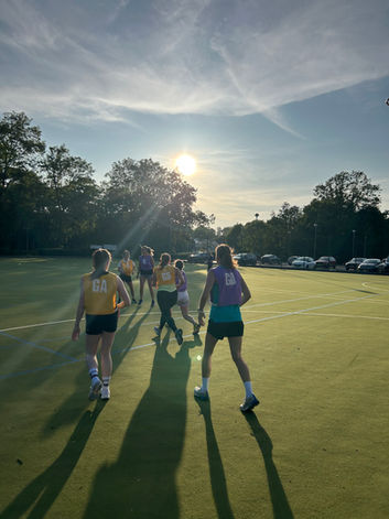 Group of young women running on a green field during sunset. Netballerz Academy